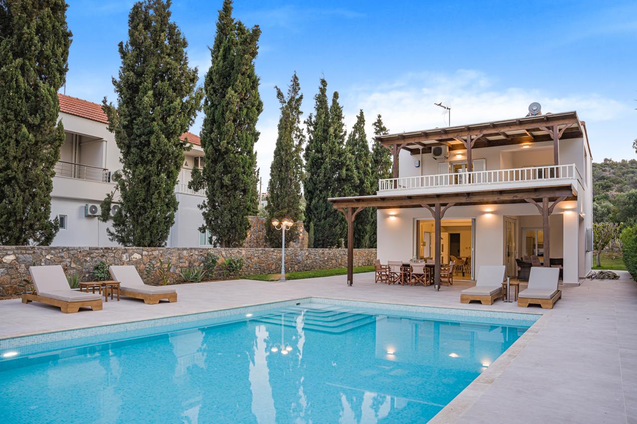 Villa and pool at dusk with loungers
